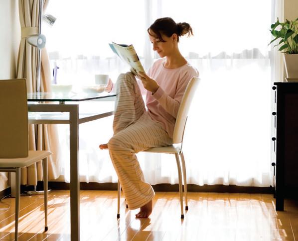 Woman in pajamas reading the newspaper and enjoying the comfort of her home